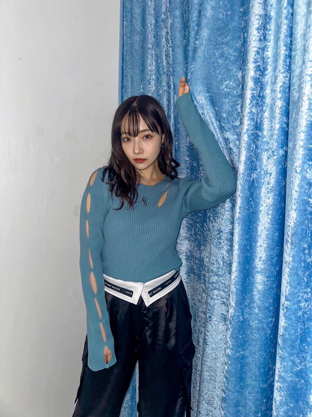 ブルー系のニット/セーター、ブラック系のカーゴパンツを着用したレディースの春コーディネートの2枚目の写真