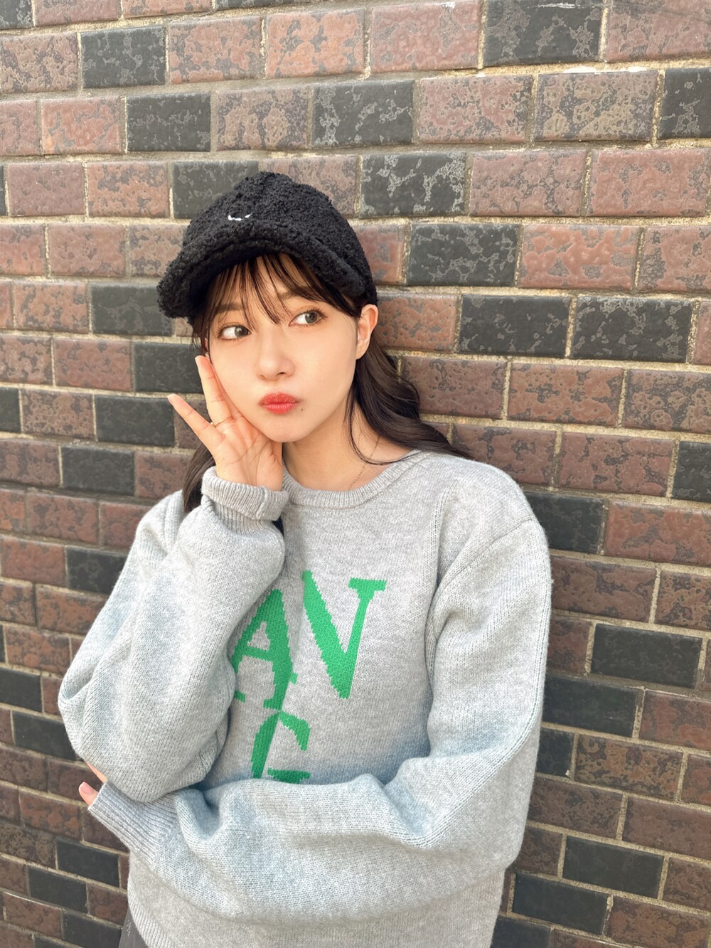 グレー系のニット/セーター、ブラック系のキャップを着用したレディースの秋コーディネートの3枚目の写真