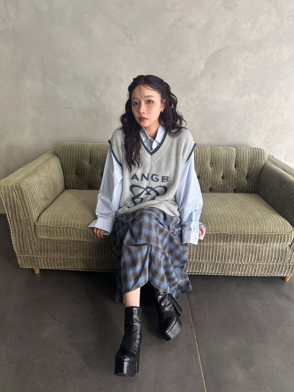 グレー系のベスト、ブルー系のスカート、ホワイト系のシャツ/ブラウスを着用したレディースの秋コーディネートの2枚目の写真