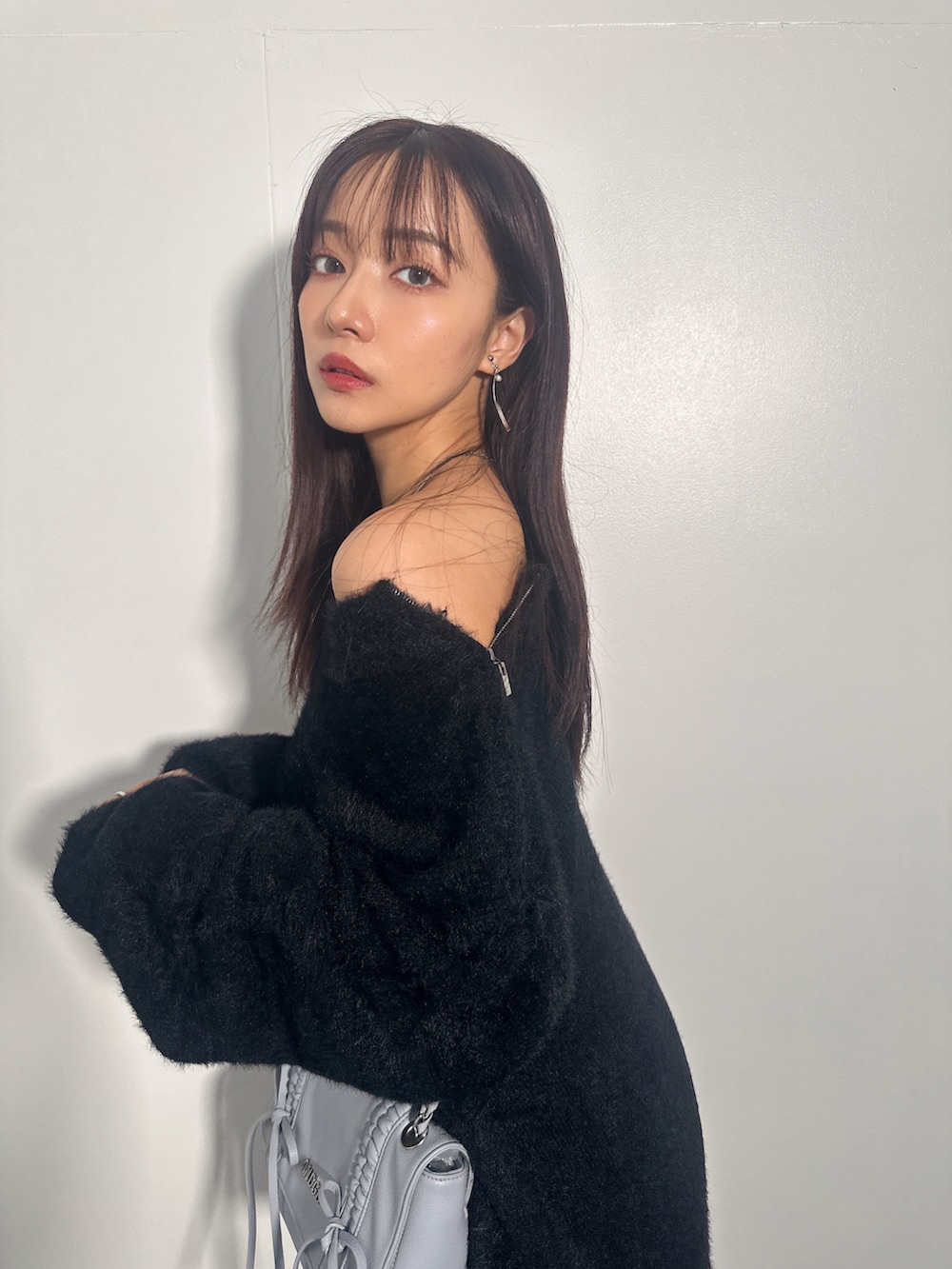 ブラック系のニット/セーター、ブルー系のショルダーバッグを着用したレディースの冬コーディネートの4枚目の写真