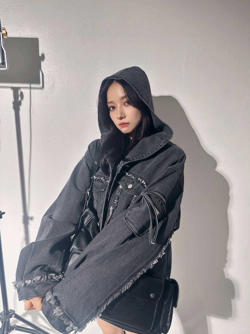 ブラック系のデニムジャケット、ブラック系のメッセンジャーバッグ、グレー系のTシャツ/カットソーを着用したレディースの冬コーディネートの3枚目の写真