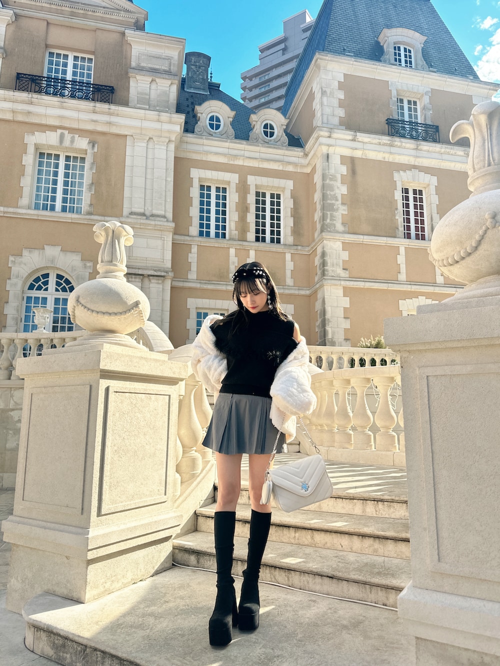 ブラック系のニット/セーター、ホワイト系のその他アウターを着用したレディースの春コーディネートの2枚目の写真