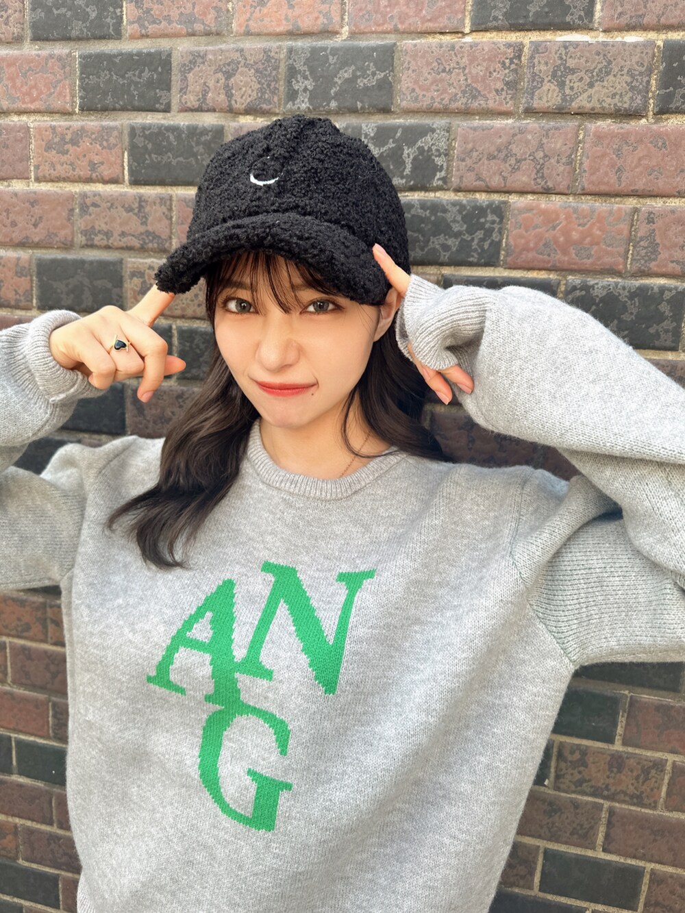 グレー系のニット/セーター、ブラック系のキャップを着用したレディースの秋コーディネートの2枚目の写真
