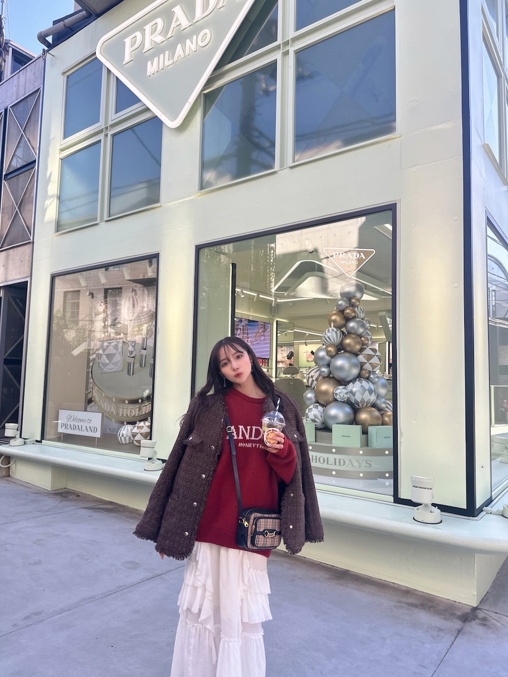 レッド系のニット/セーター、ブラウン系のその他アウター、ホワイト系のスカートを着用したレディースの冬コーディネートの3枚目の写真