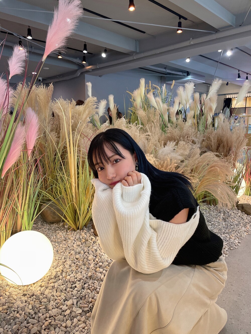 ブラック系のニット/セーター、ホワイト系のスカートを着用したレディースの春コーディネートの4枚目の写真