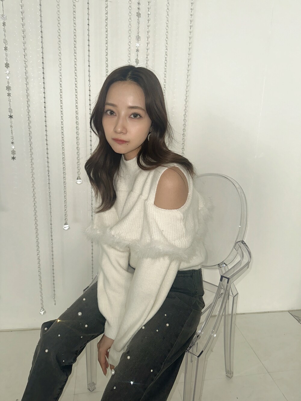 ホワイト系のニット/セーター、ブラック系のデニムパンツを着用したレディースの春コーディネートの2枚目の写真