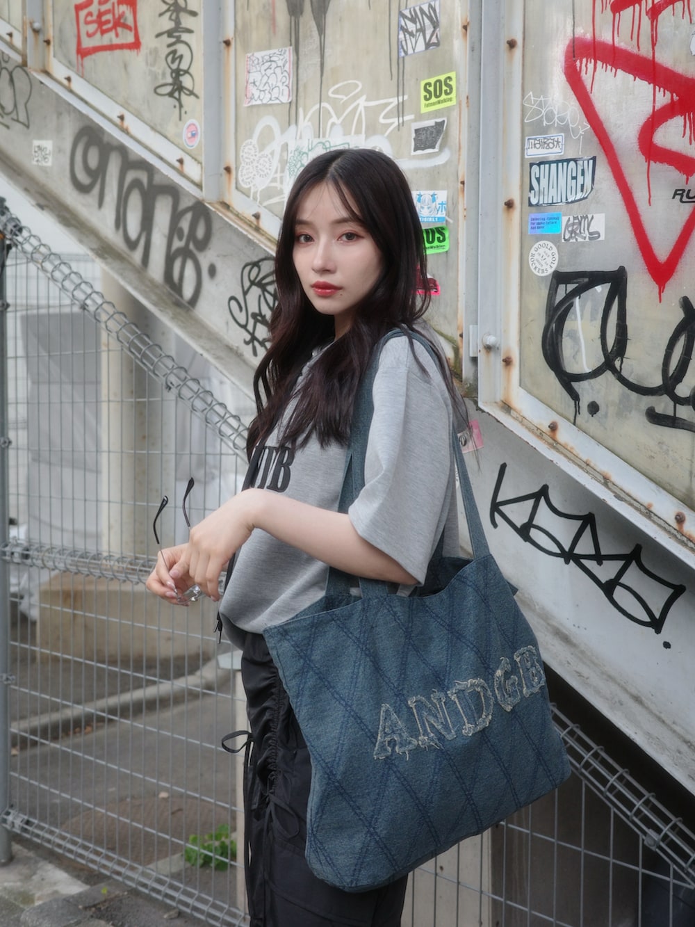 グレー系のパーカー、ブラック系のカーゴパンツ、ブラック系のトートバッグを着用したレディースの秋コーディネートの5枚目の写真