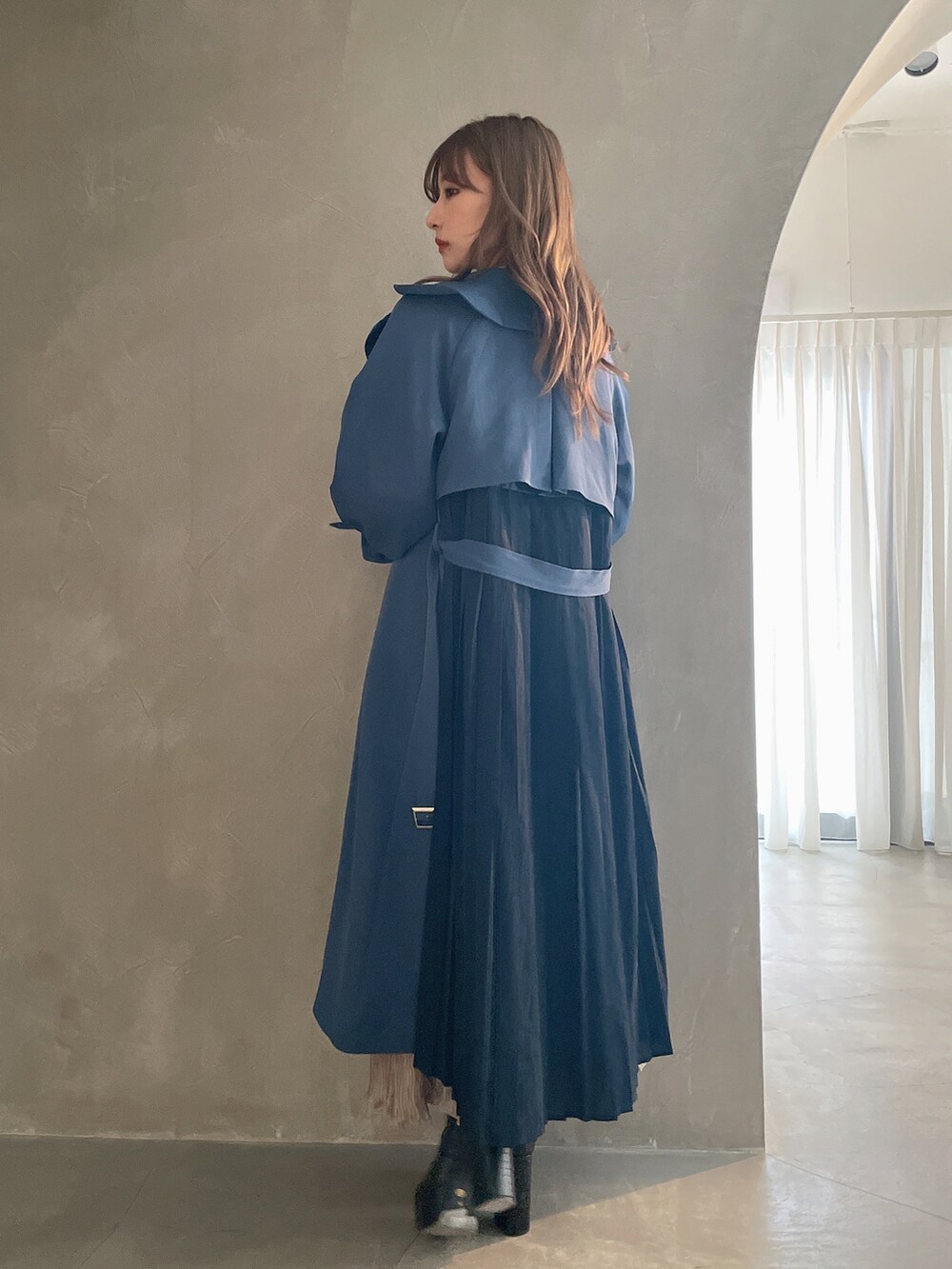 ベージュ系のワンピース、ブラック系のブーツ、グレー系のトレンチコートを着用したレディースの秋コーディネートの2枚目の写真