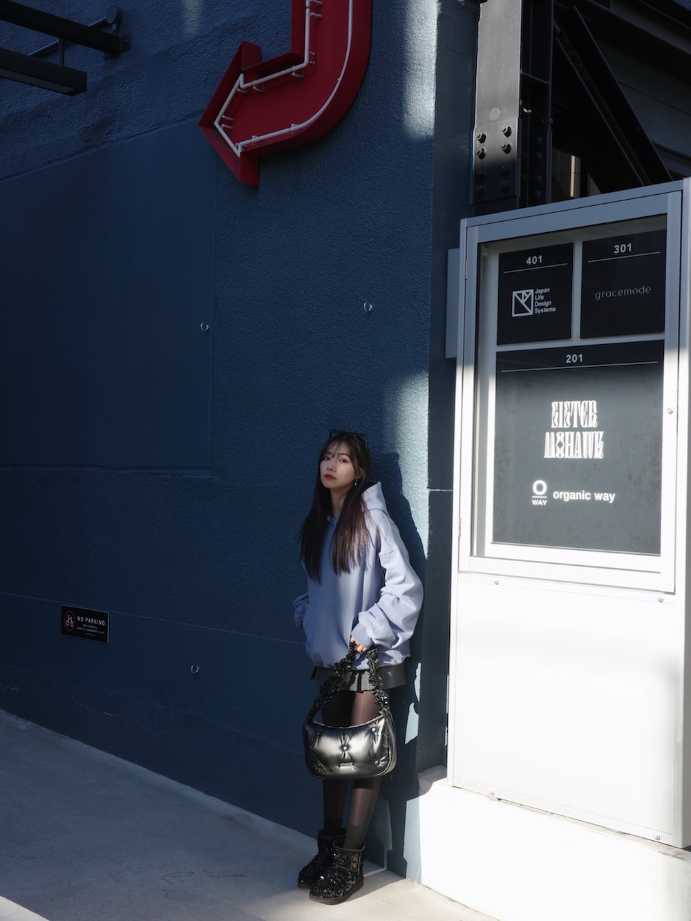 ブルー系のパーカー、ブラック系のショルダーバッグを着用したレディースの春コーディネートの2枚目の写真