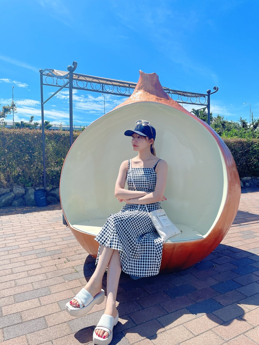 ブラック系のワンピース、ホワイト系のショルダーバッグ、ホワイト系のサンダルを着用したレディースの秋コーディネートの2枚目の写真