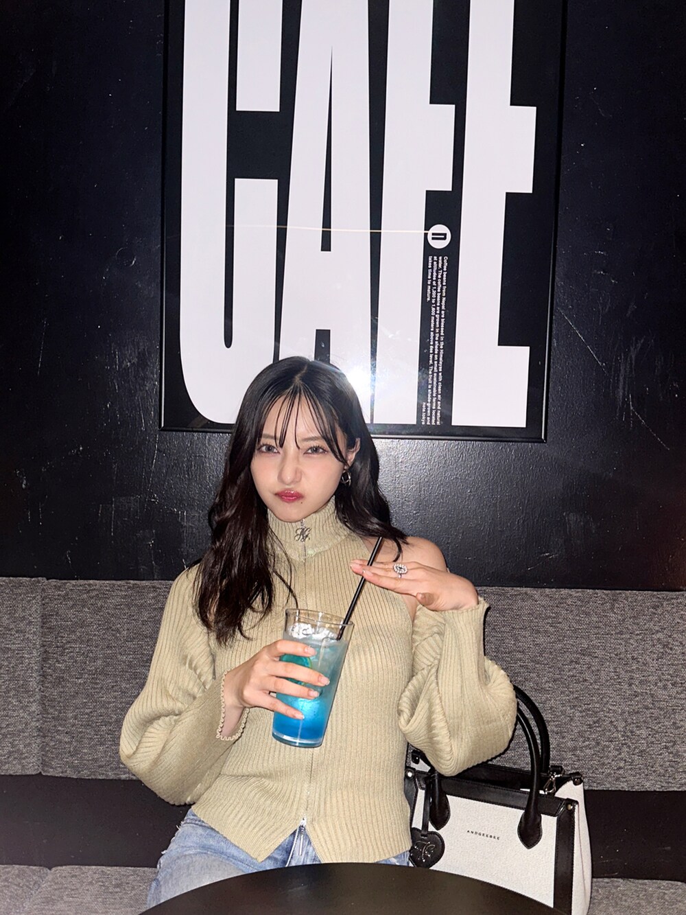 グリーン系のニット/セーター、ブラック系のショルダーバッグを着用したレディースの冬コーディネートの2枚目の写真