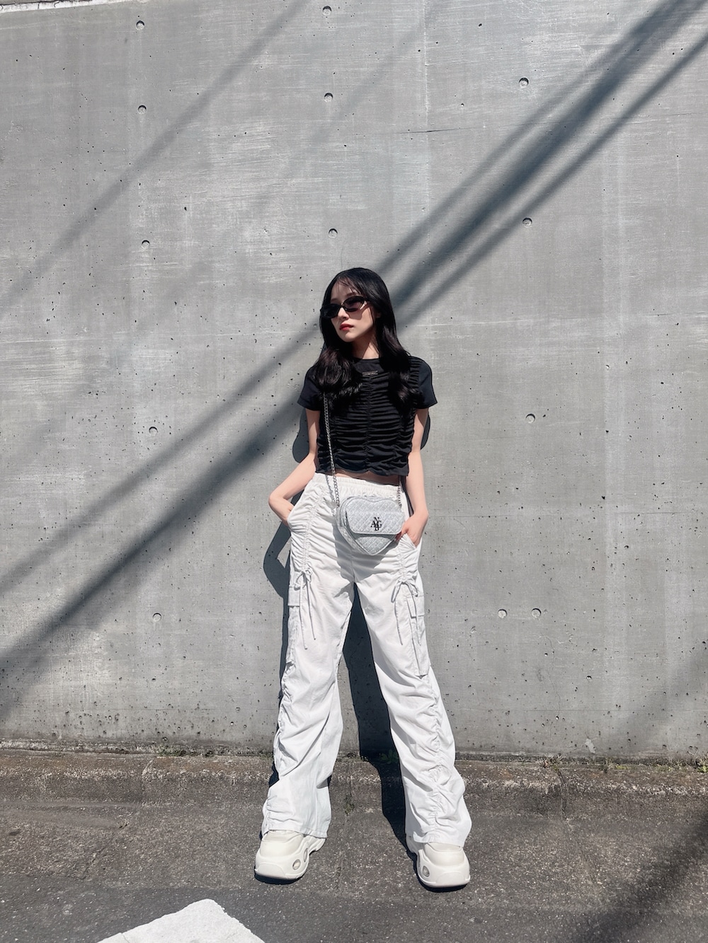 ブラック系のTシャツ/カットソー、ベージュ系のカーゴパンツ、ホワイト系のスニーカーを着用したレディースの夏コーディネートの4枚目の写真