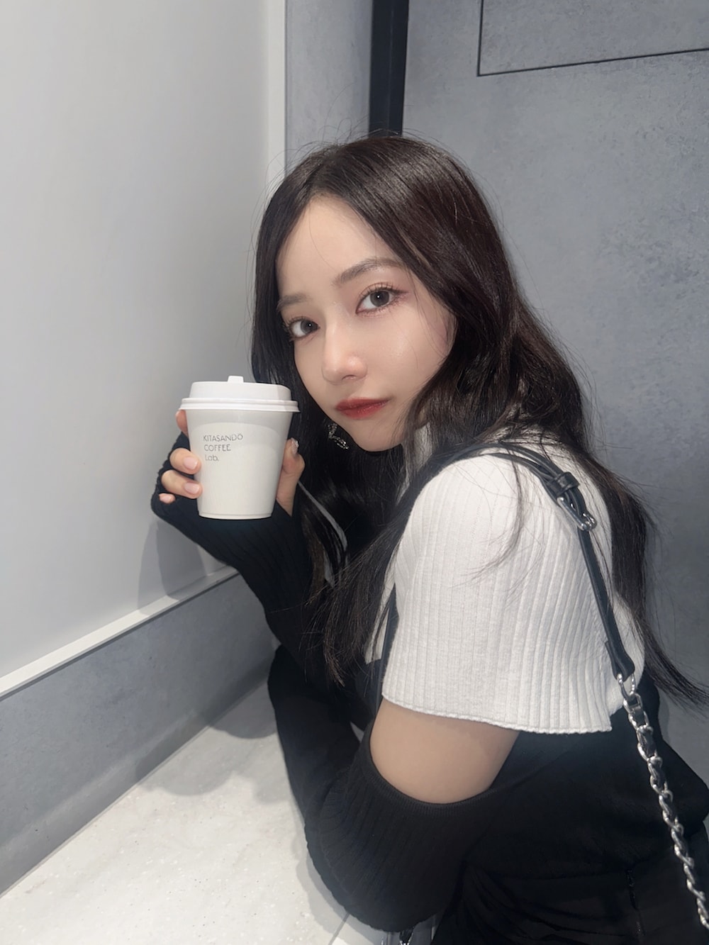 ホワイト系のニット/セーター、ブラック系のスカート、ブラック系のショルダーバッグを着用したレディースの冬コーディネートの5枚目の写真