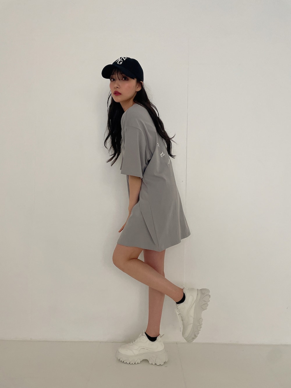 グレー系のTシャツ/カットソー、ブラック系のキャップを着用したレディースの夏コーディネートの2枚目の写真