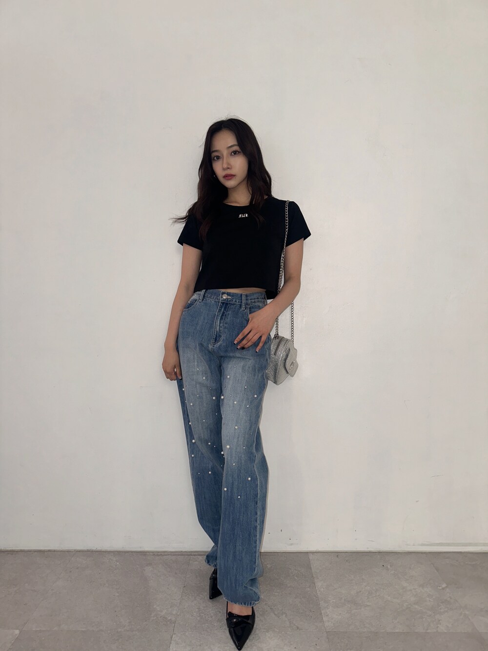 ブラック系のTシャツ/カットソー、ブルー系のデニムパンツ、シルバー系のショルダーバッグを着用したレディースの秋コーディネートの2枚目の写真