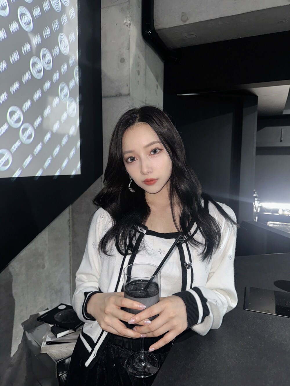 ホワイト系のアンサンブル、グレー系のショルダーバッグ、ブラック系のスカートを着用したレディースの秋コーディネートの4枚目の写真