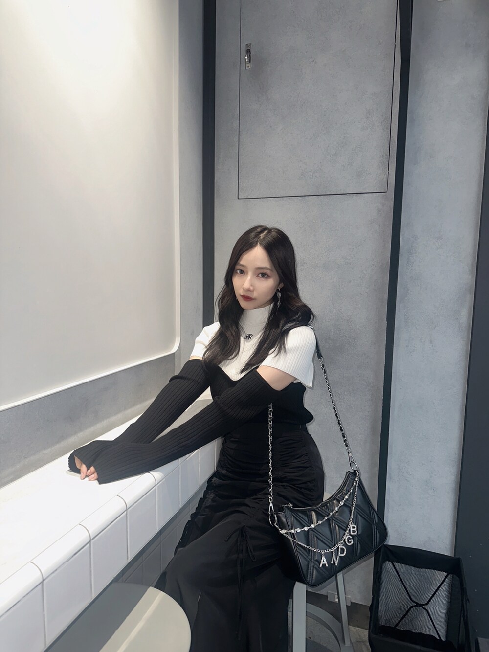 ホワイト系のニット/セーター、ブラック系のスカート、ブラック系のショルダーバッグを着用したレディースの冬コーディネートの2枚目の写真