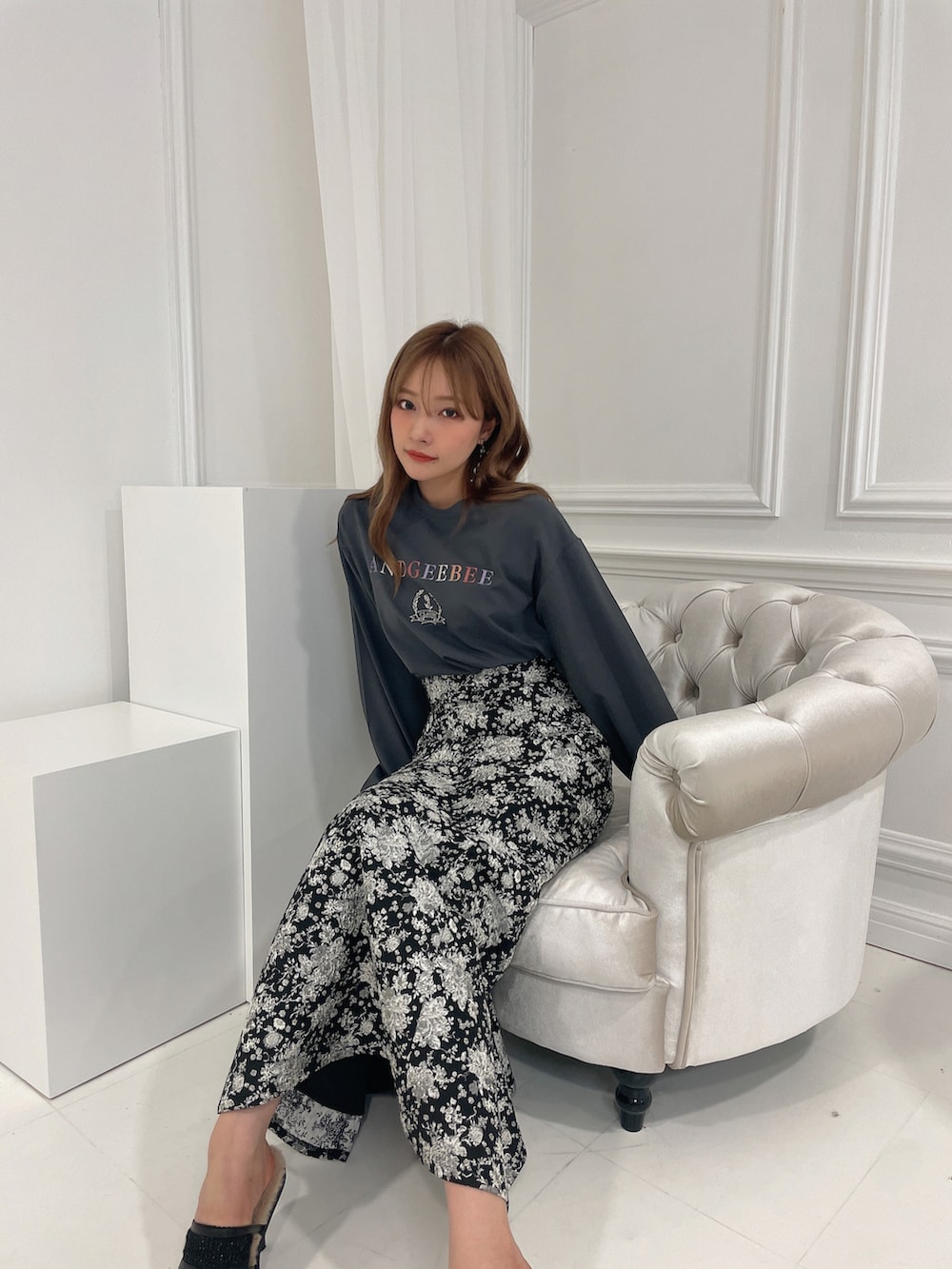 グレー系のTシャツ/カットソー、ブラック系のスカート、ブラック系のサンダルを着用したレディースの秋コーディネートの4枚目の写真