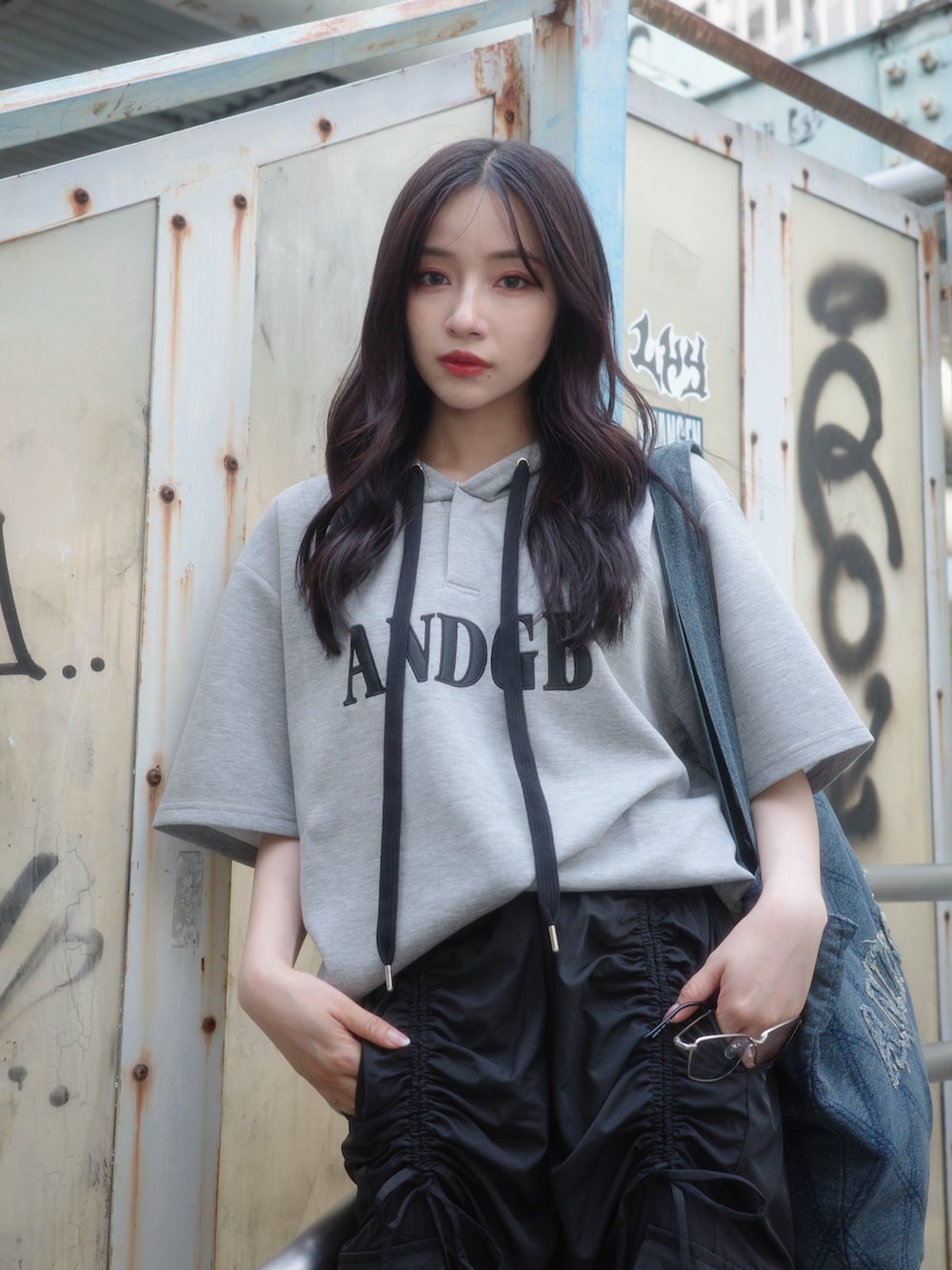 グレー系のパーカー、ブラック系のカーゴパンツ、ブラック系のトートバッグを着用したレディースの秋コーディネートの4枚目の写真