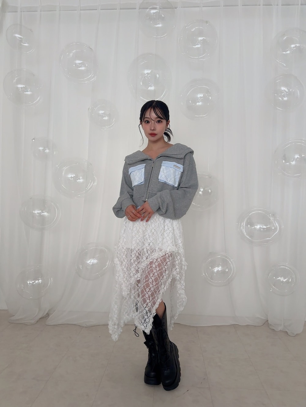 グレー系のパーカー、ホワイト系のスカートを着用したレディースの夏コーディネートの2枚目の写真