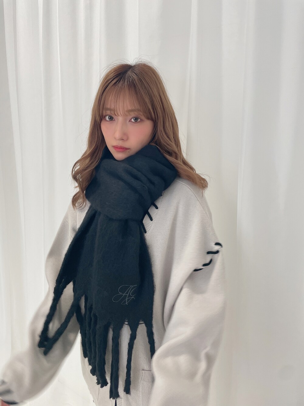 グレー系のカーディガン/ボレロ、ブラック系のマフラーを着用したレディースの冬コーディネートの2枚目の写真