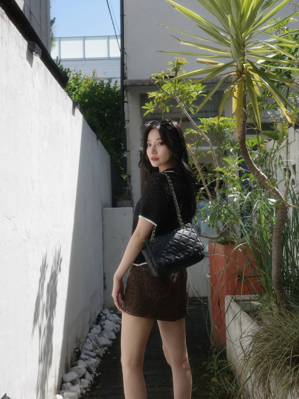 ブラック系のポロシャツ、ブラウン系のスカート、ブラック系のサンダルを着用したレディースの秋コーディネートの2枚目の写真