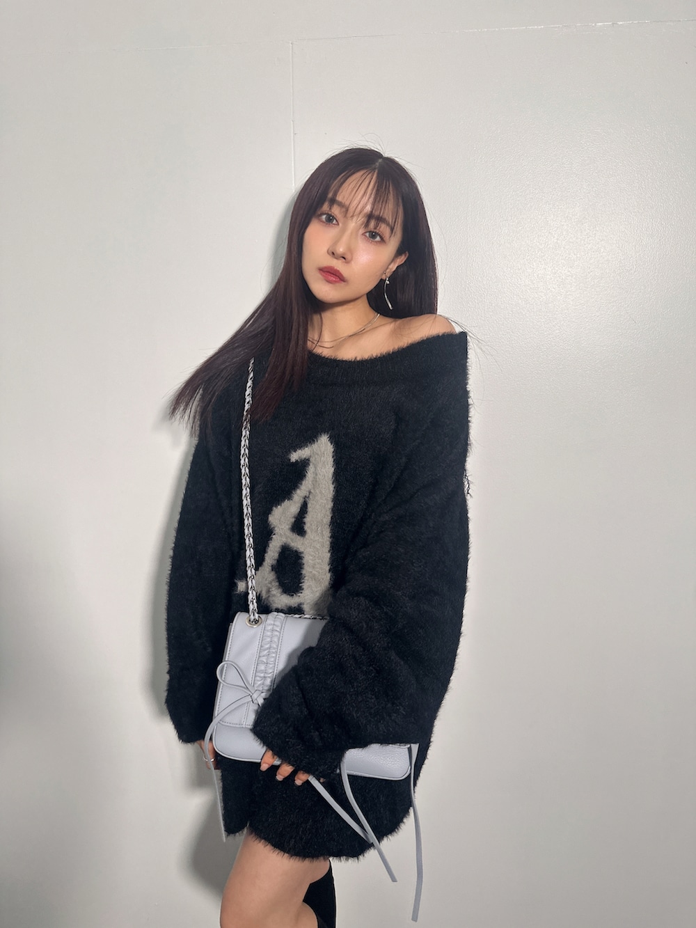 ブラック系のニット/セーター、ブルー系のショルダーバッグを着用したレディースの冬コーディネートの2枚目の写真