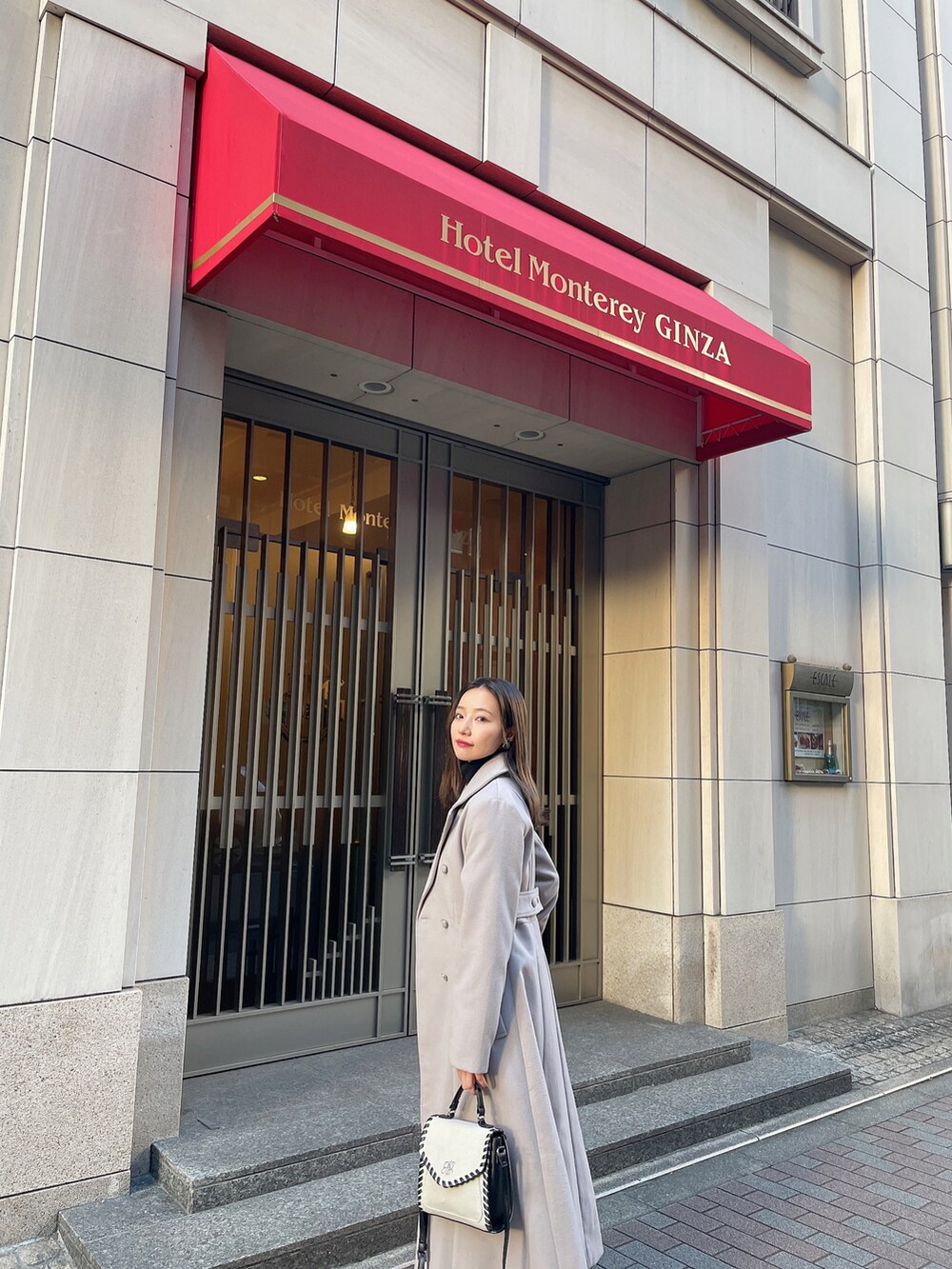 グレー系のチェスターコート、ブラック系のその他シューズ、ベージュ系のショルダーバッグを着用したレディースの春コーディネートの3枚目の写真