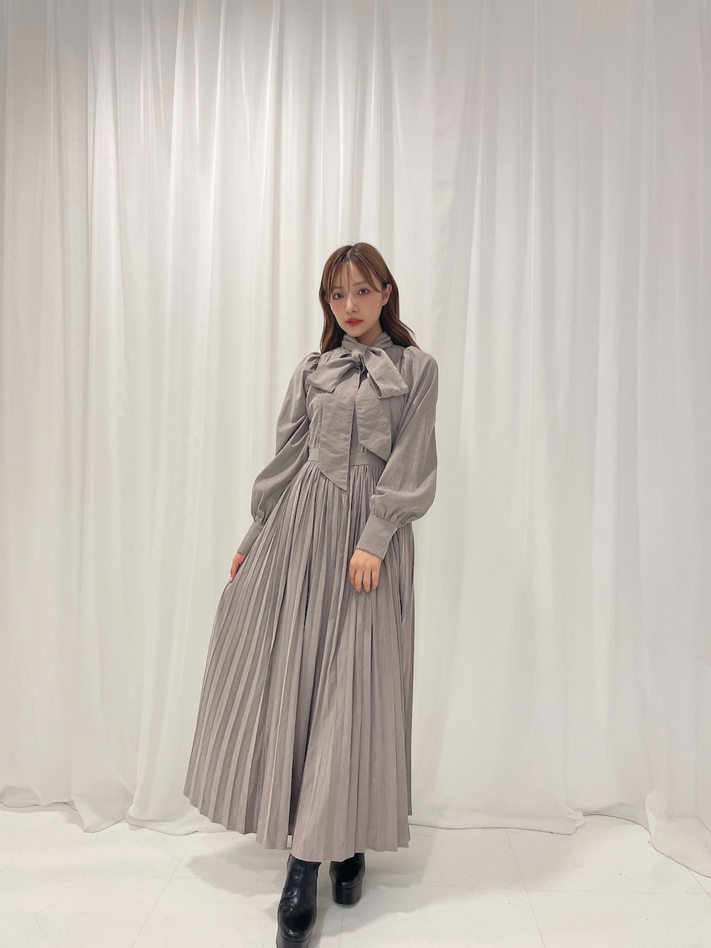 ブラック系のブーツ、グレー系のワンピースを着用したレディースの冬コーディネートの2枚目の写真