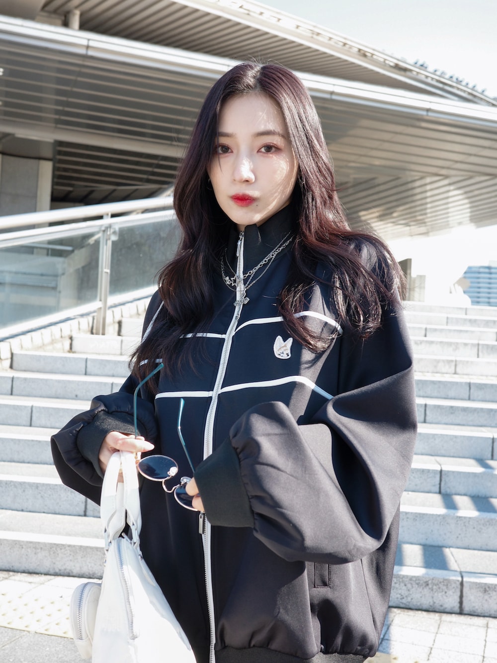 ブラック系のジャージ、ブラック系のスカート、グレー系のショルダーバッグを着用したレディースの夏コーディネートの5枚目の写真