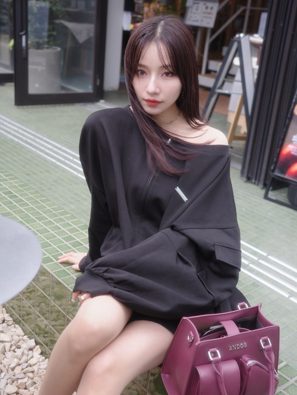 ブラック系のパーカー、ブラック系のスカート、レッド系のショルダーバッグを着用したレディースの夏コーディネートの4枚目の写真