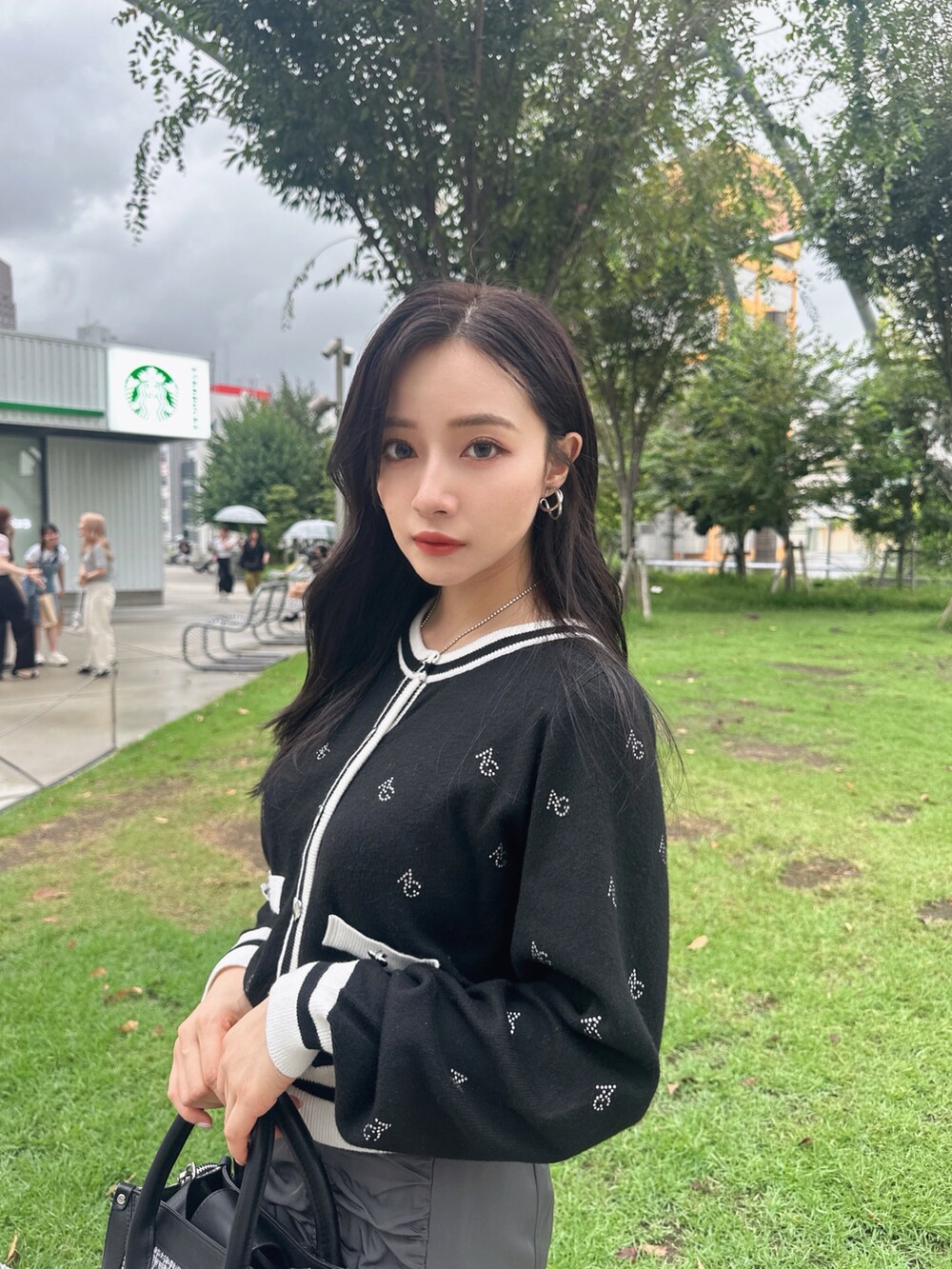 グレー系のスカート、ホワイト系のアンサンブルを着用したレディースの秋コーディネートの3枚目の写真