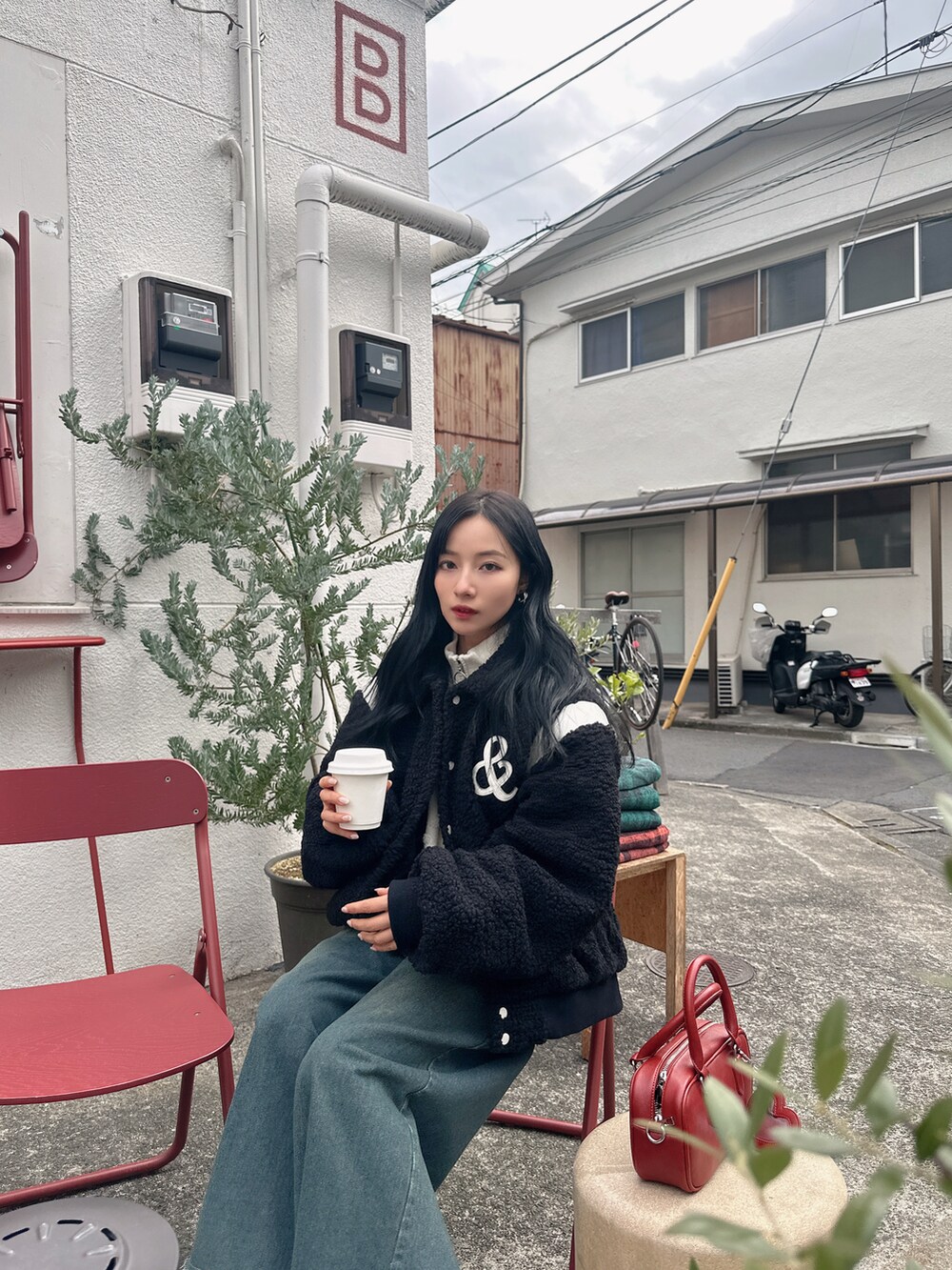 ブラック系のスタジャン、レッド系のショルダーバッグを着用したレディースの春コーディネートの3枚目の写真