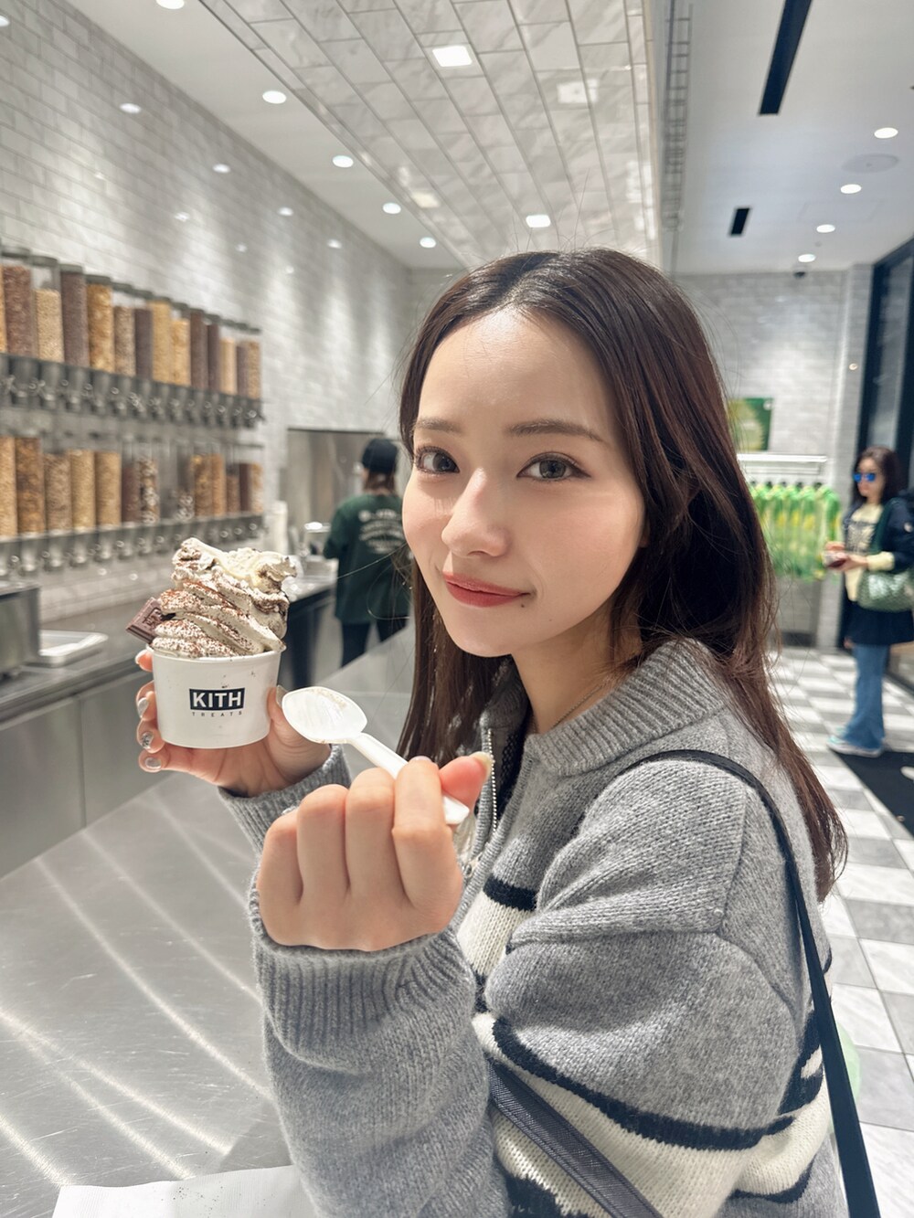 グレー系のトップス、ブラック系のショルダーバッグを着用したレディースの春コーディネートの2枚目の写真