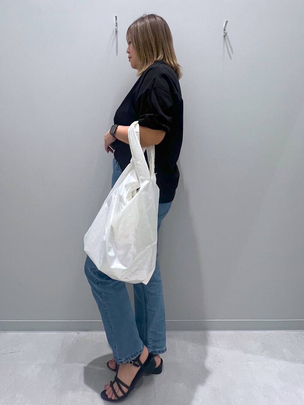 ブラック系のTシャツ/カットソー、ブルー系のデニムパンツ、ホワイト系のトートバッグを着用したレディースの夏コーディネートの2枚目の写真