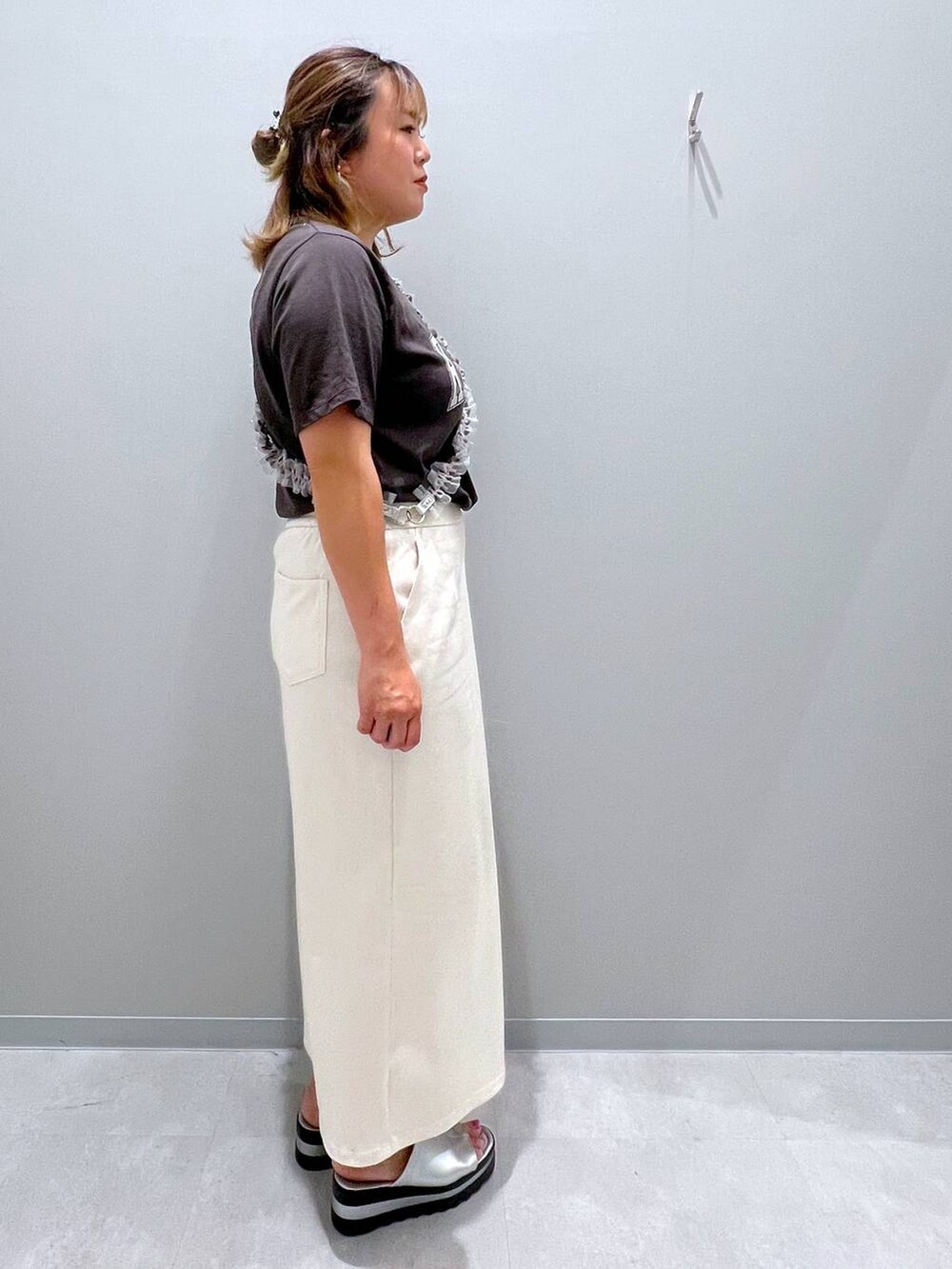 グレー系のTシャツ/カットソー、ホワイト系のデニムスカート、グレー系のスマホグッズを着用したレディースの夏コーディネートの4枚目の写真