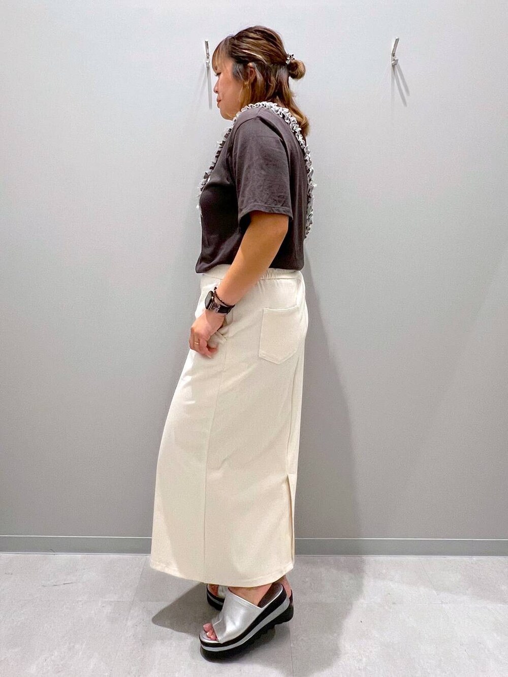 グレー系のTシャツ/カットソー、ホワイト系のデニムスカート、グレー系のスマホグッズを着用したレディースの夏コーディネートの2枚目の写真