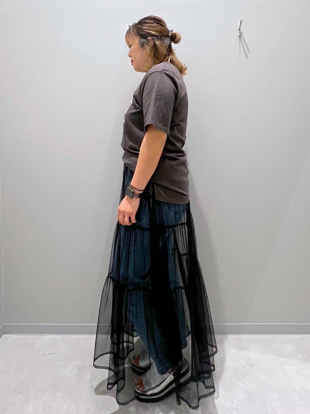 グレー系のTシャツ/カットソー、ブルー系のデニムパンツ、ブラック系のスカートを着用したレディースの夏コーディネートの2枚目の写真