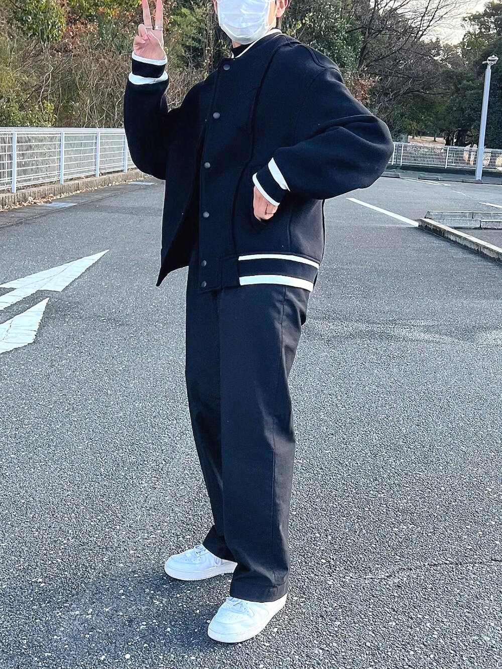 ブラック系のチノパンツ、ホワイト系のスニーカー、ブラック系のジャケット/アウターを着用したメンズの冬コーディネートの2枚目の写真