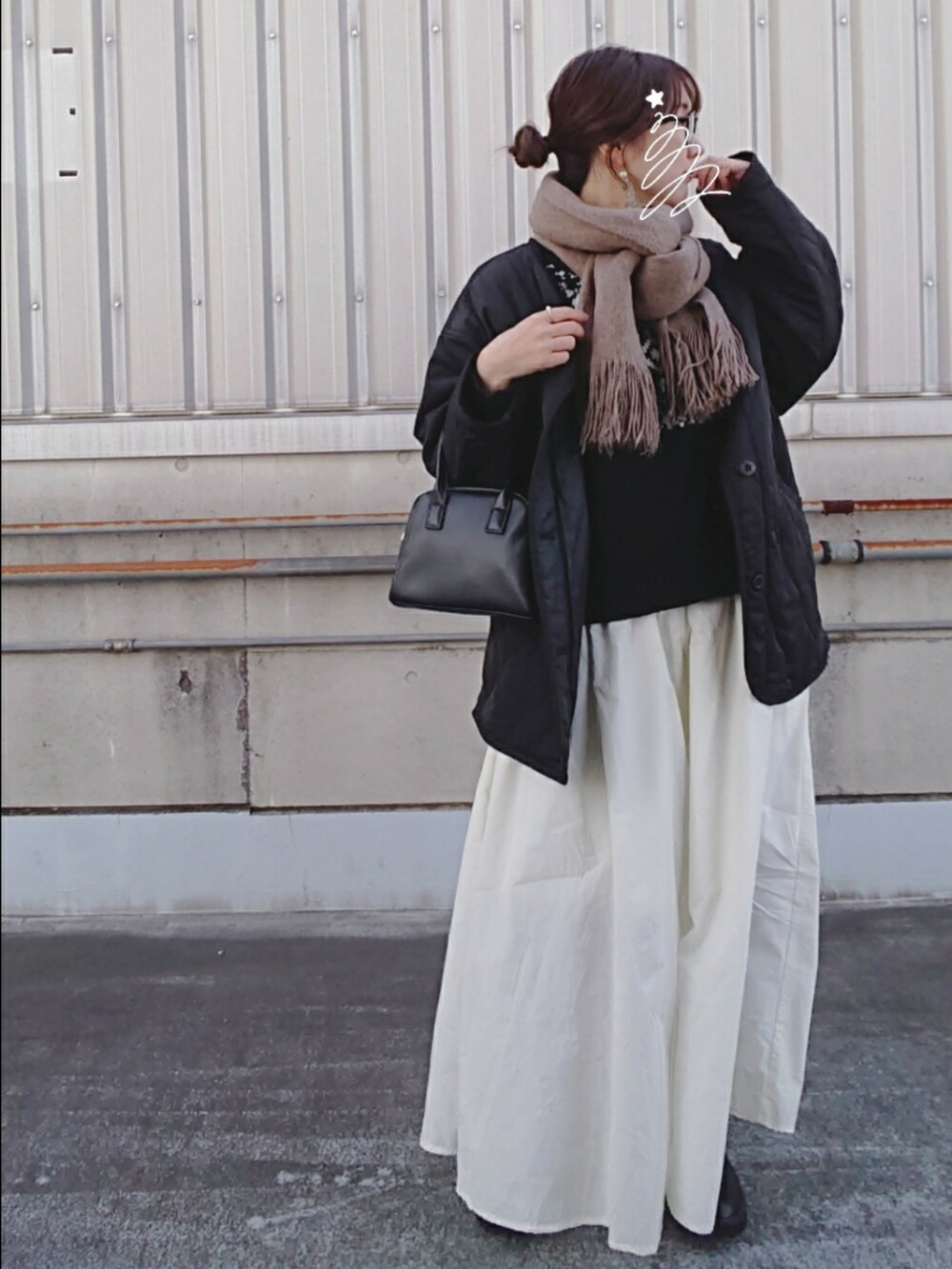 ホワイト系のスカート、ブラック系のブルゾン、ブラック系のボストンバッグを着用したレディースの冬コーディネートの2枚目の写真