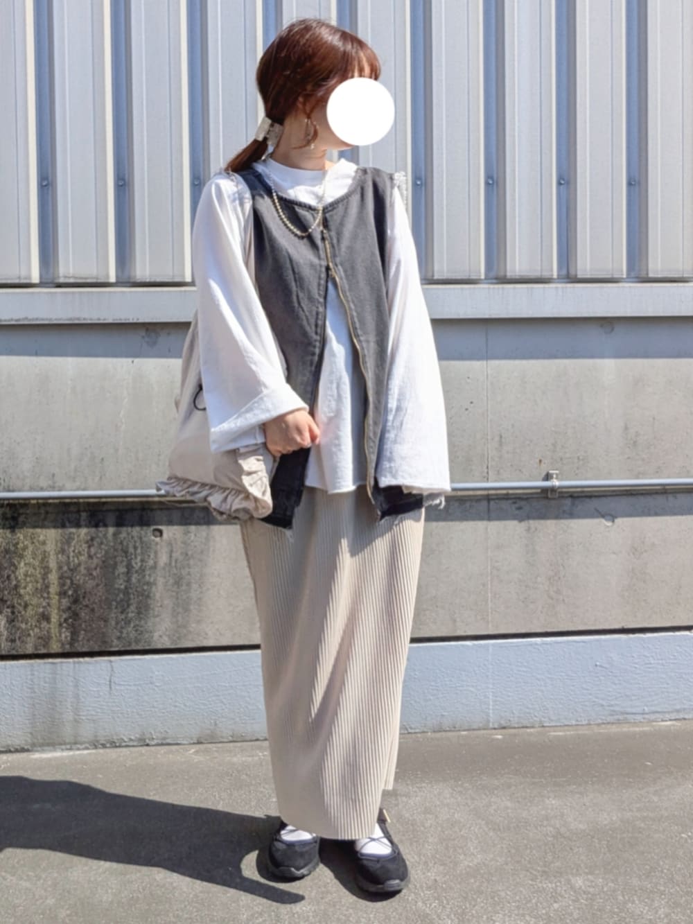 ブラック系のベスト、ホワイト系のTシャツ/カットソー、ブラック系のスニーカーを着用したレディースの春コーディネートの2枚目の写真