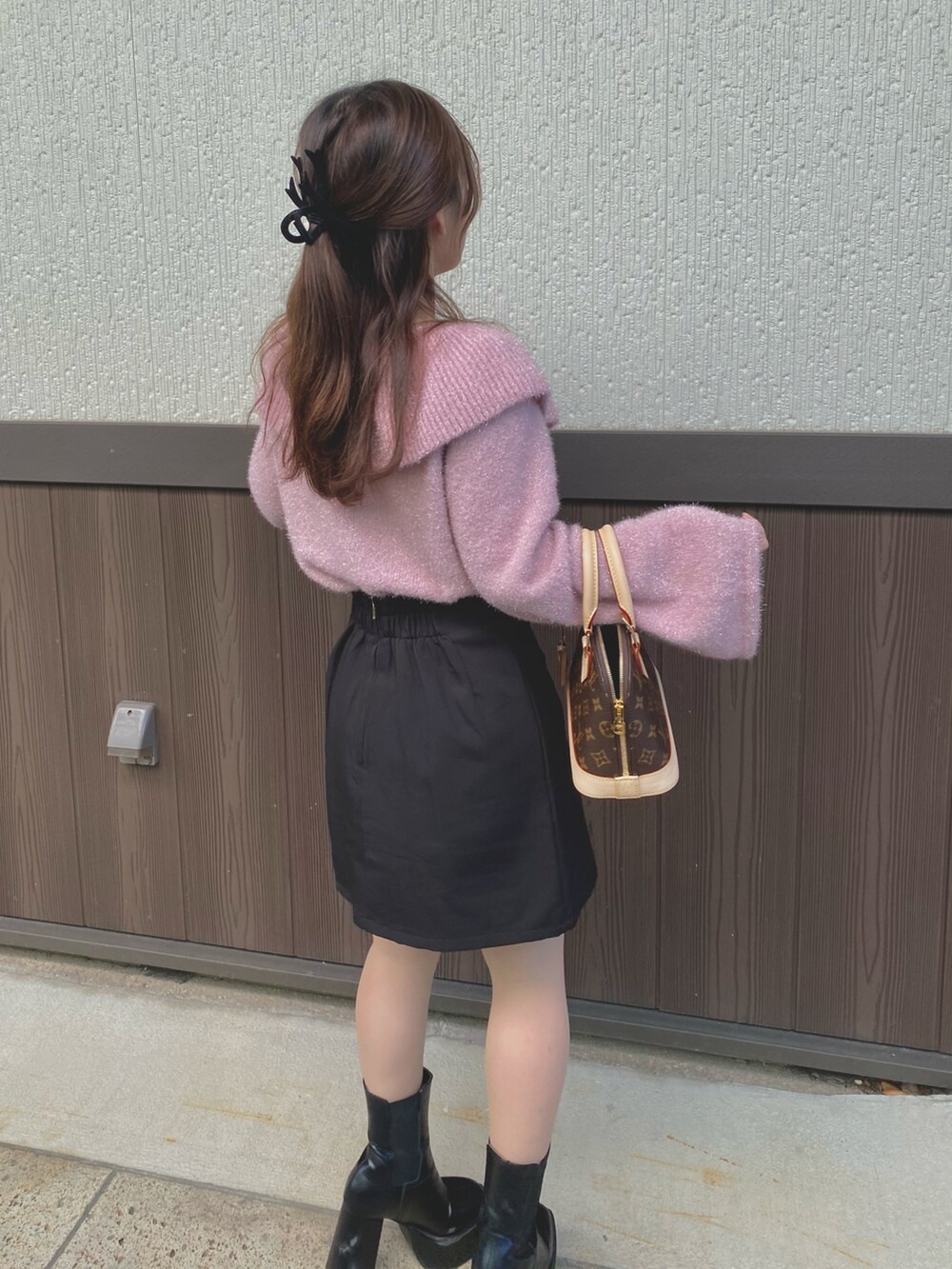 ピンク系のニット/セーター、ブラック系のスカート、ブラック系のブーツを着用したレディースの春コーディネートの2枚目の写真