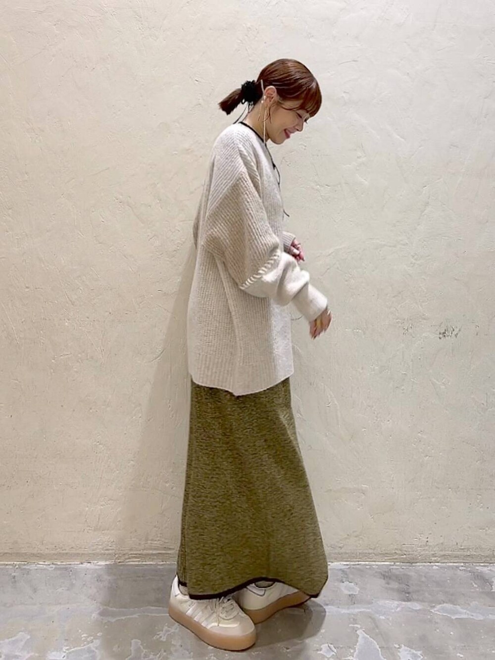 イエロー系のスカート、ベージュ系のニット/セーター、ブラック系のチョーカーを着用したレディースの秋コーディネートの4枚目の写真