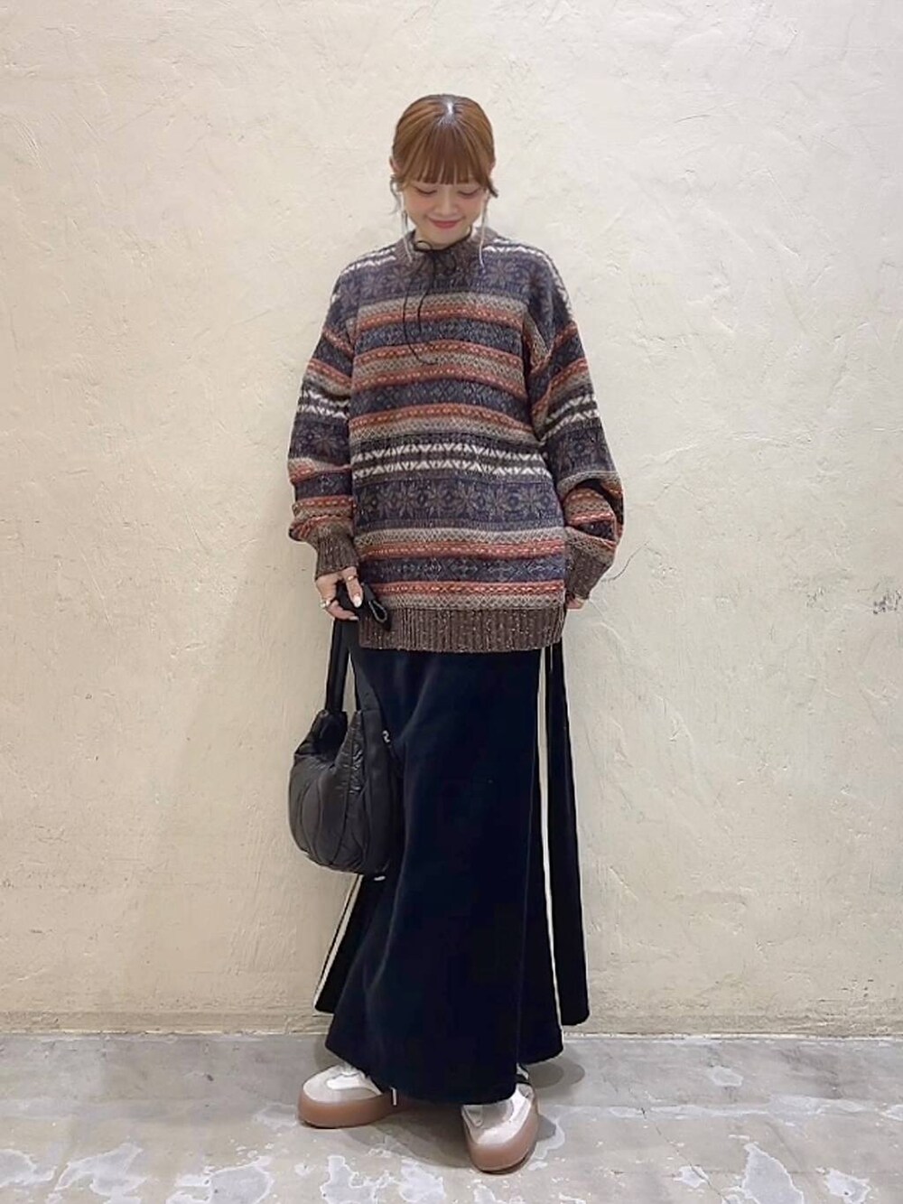 ブラック系のショルダーバッグ、ブラウン系のニット/セーター、ブラック系のスカートを着用したレディースの冬コーディネートの7枚目の写真