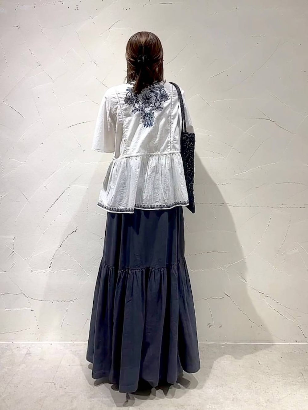 グレー系のスカート、ホワイト系のシャツ/ブラウス、ブラック系のトートバッグを着用したレディースの春コーディネートの6枚目の写真