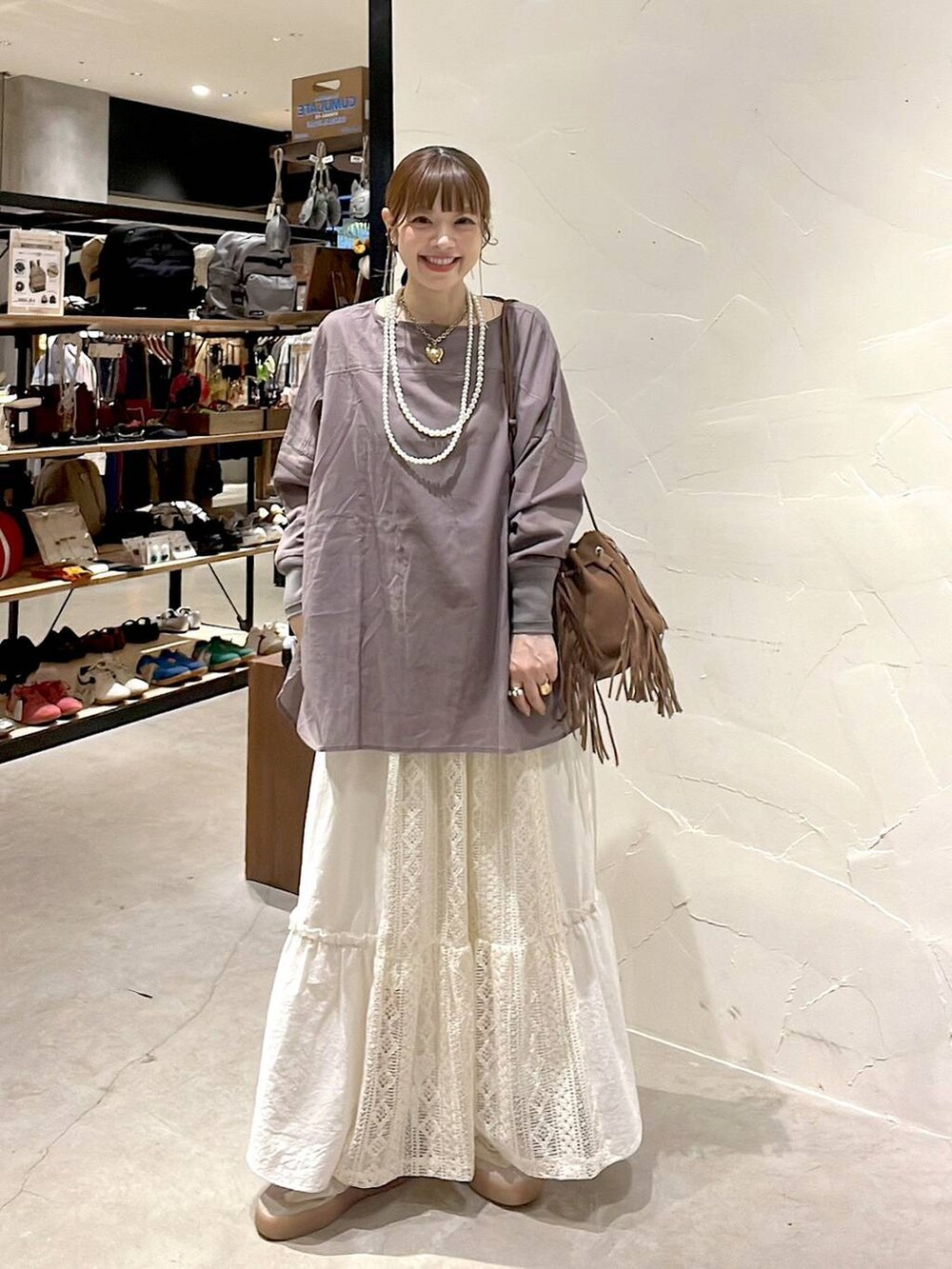 ベージュ系のスカート、ブラウン系のショルダーバッグ、ベージュ系のネックレスを着用したレディースの夏コーディネートの4枚目の写真