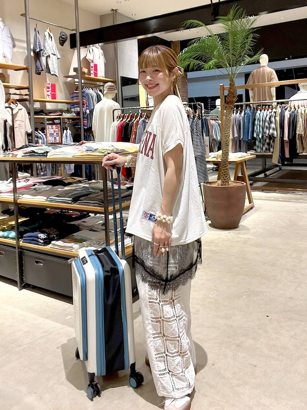 ホワイト系のその他パンツ、ベージュ系のスーツケース/キャリーバッグ、ホワイト系のバックパック/リュックを着用したレディースの夏コーディネートの2枚目の写真