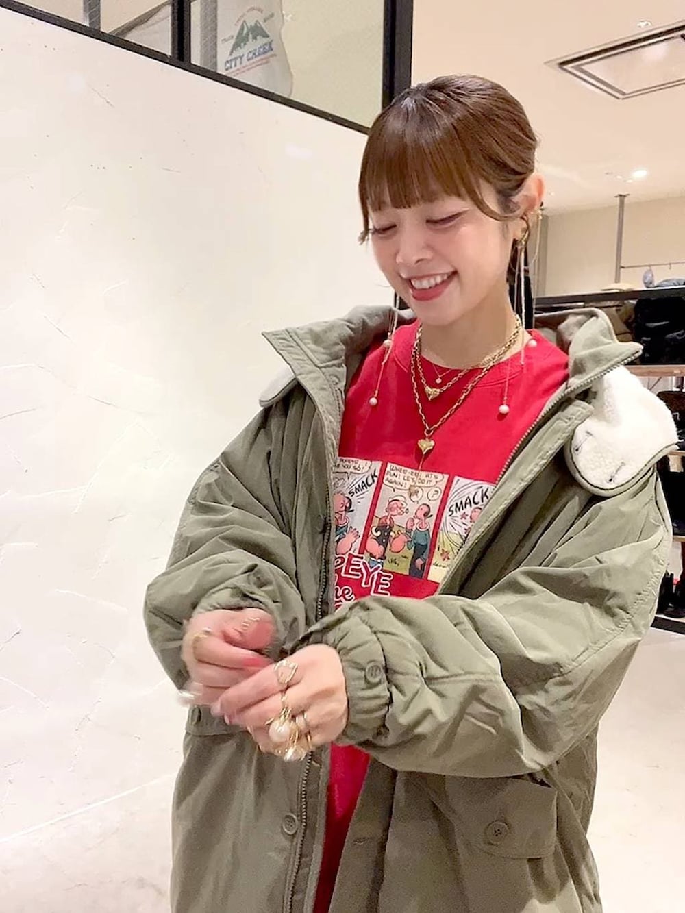 グリーン系のブルゾン、グレー系のその他パンツ、レッド系のスウェットを着用したレディースの冬コーディネートの6枚目の写真