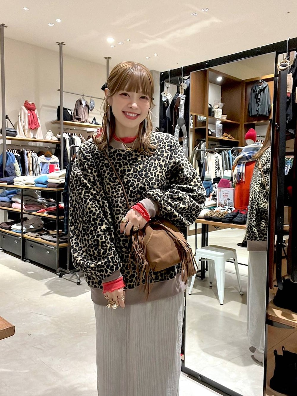 レッド系のTシャツ/カットソー、グレー系のスカート、ベージュ系のスニーカーを着用したレディースの冬コーディネートの2枚目の写真