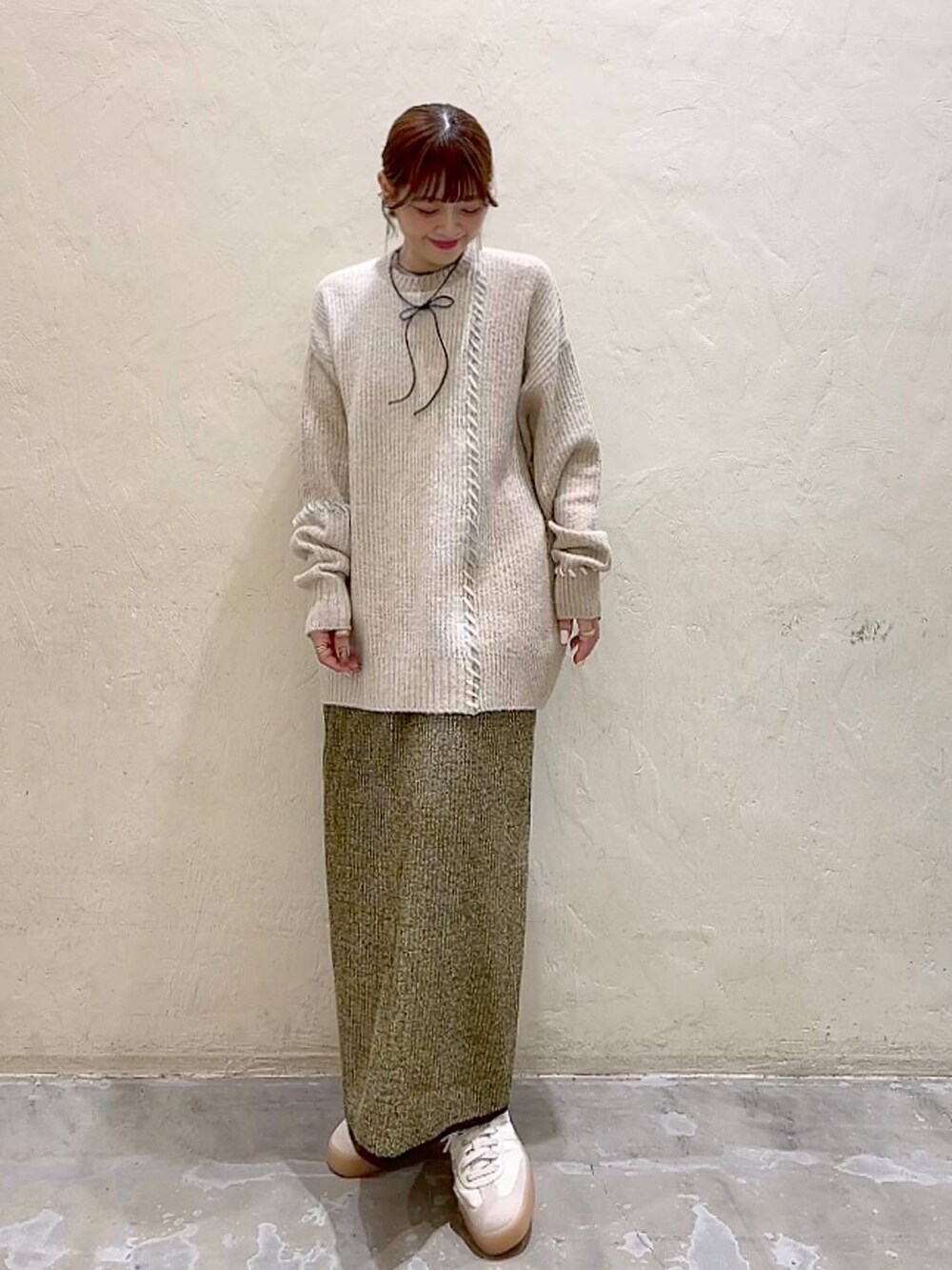 イエロー系のスカート、ベージュ系のニット/セーター、ブラック系のチョーカーを着用したレディースの秋コーディネートの9枚目の写真